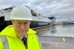 Simon Eardley in a hi viz jacket and hard hat in front of a steamer packet